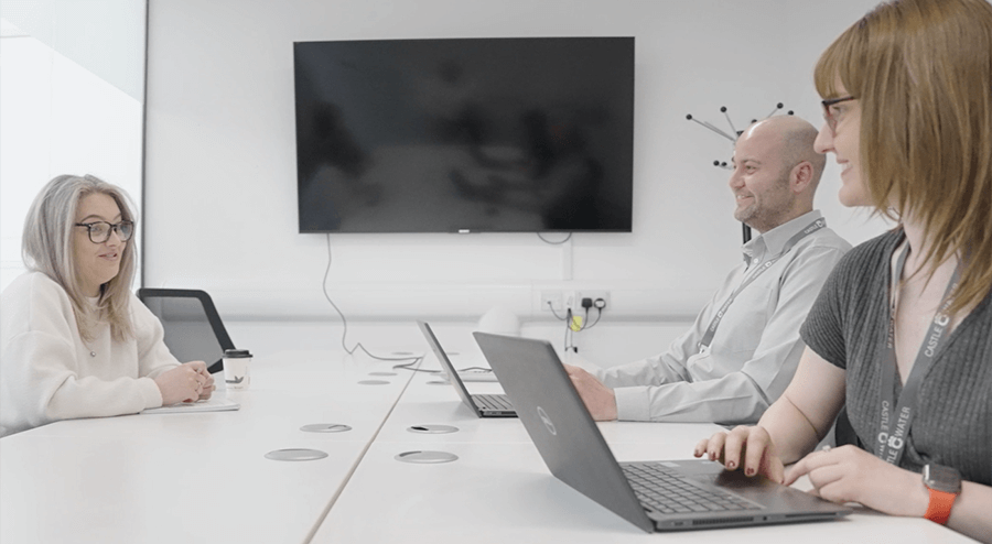 A team of professionals at a desk on laptops