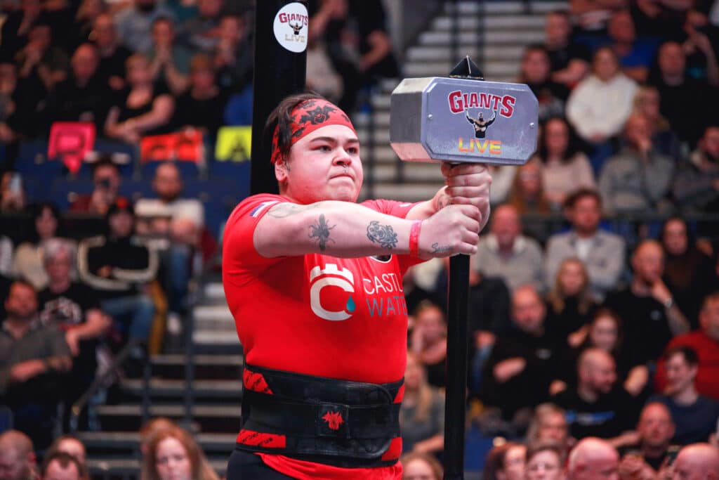 Strength athlete performing hammer hold in castle water shirt