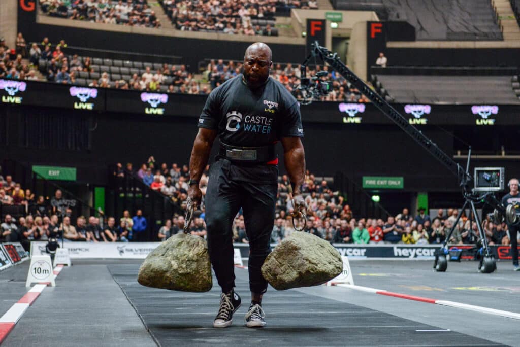 strongman in castle water doing a dinnie walk