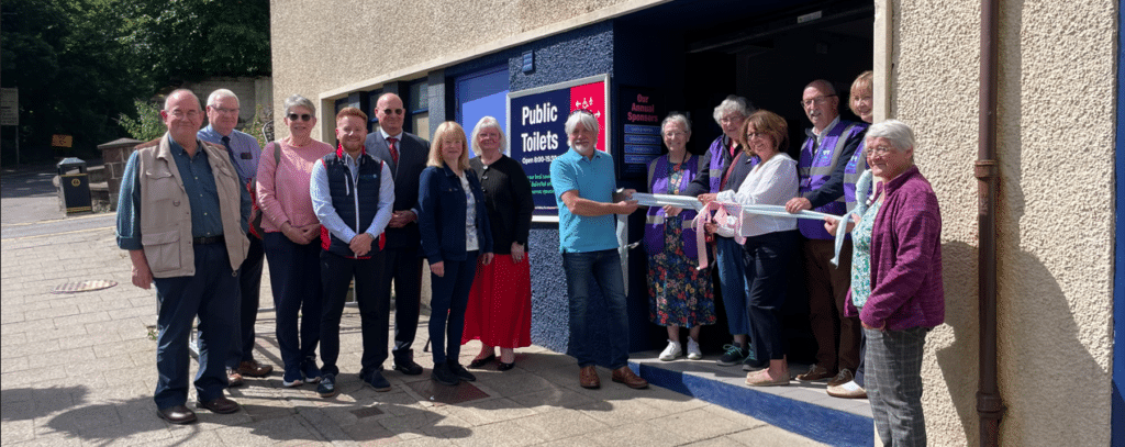 Group of people gathered outside a building for a ribbon-cutting ceremony.