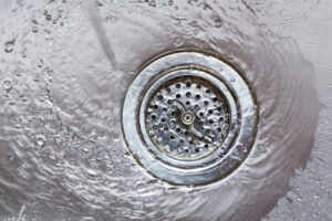 Water flowing going down drain in stainless steel kitchen sink