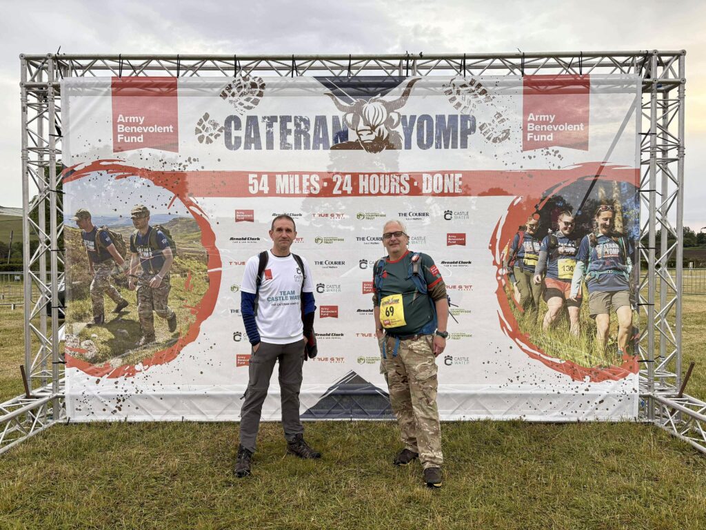 Castle Water employees Kevin and Peter standing in front of the 2025 Cateran Yomp event sign